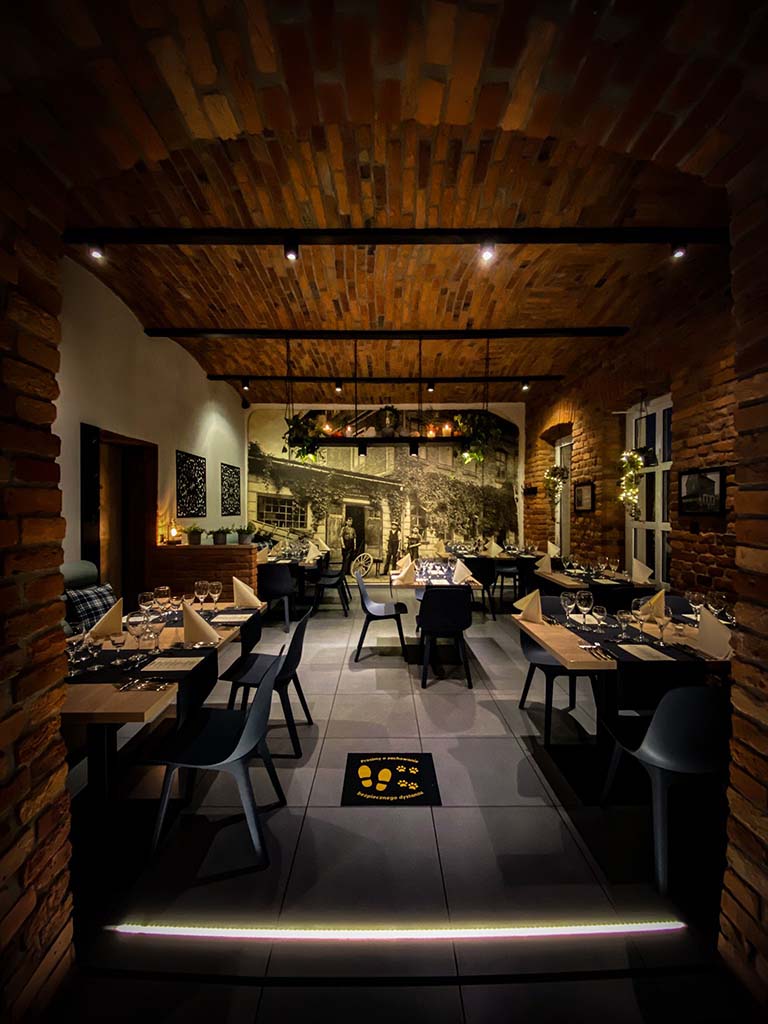 Bistro Piekarnik wieczorem — podświetlony szyld i ciepłe światło w oknach