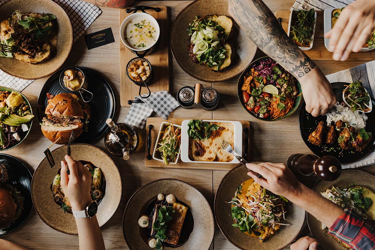 Stół pełen dań Bistro Piekarnik widziany z góry — zupy, burgery, sałaty i ziemniaki z pieca